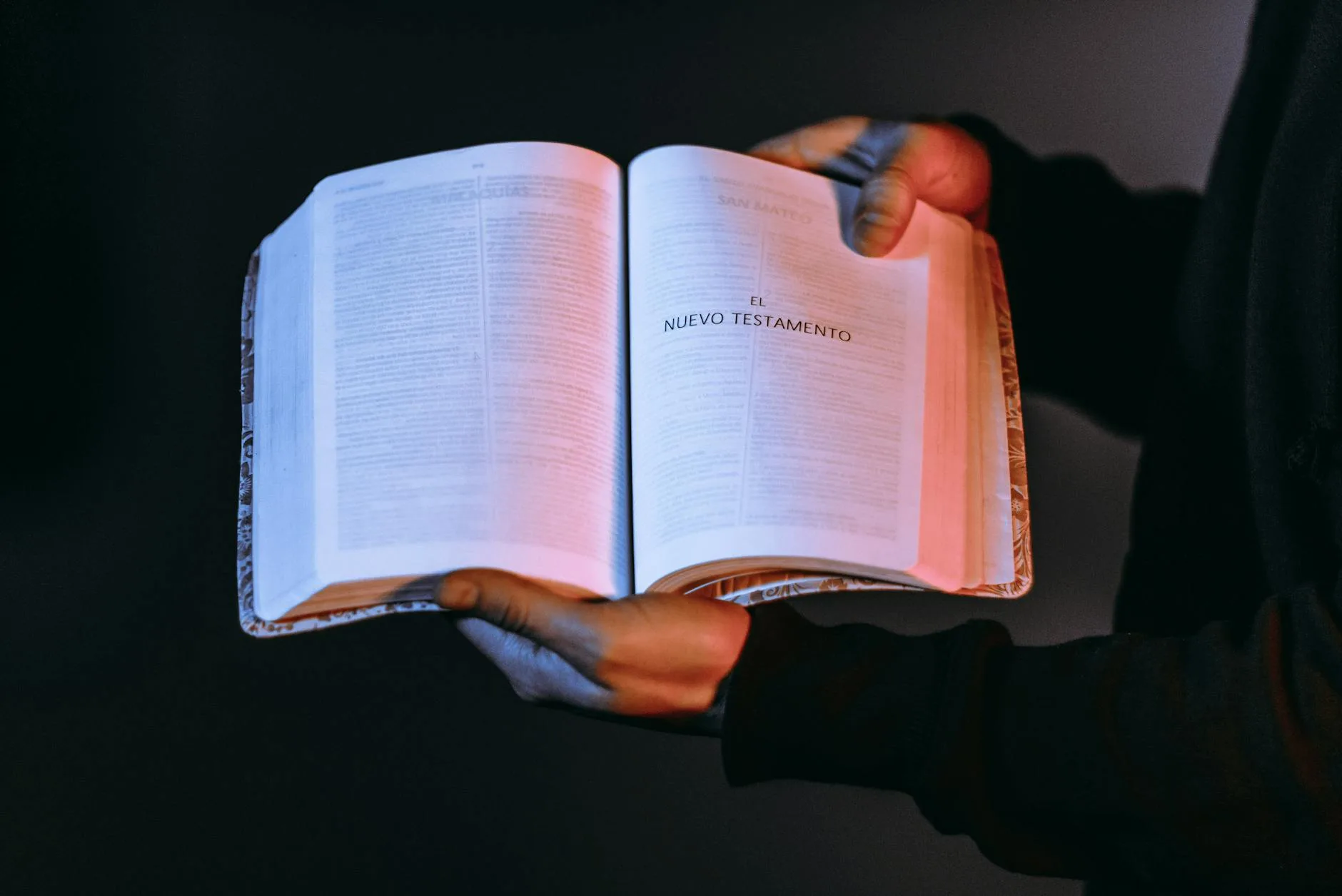 Osoba trzyma otwartą Biblię z widocznym Nowym Testamentem